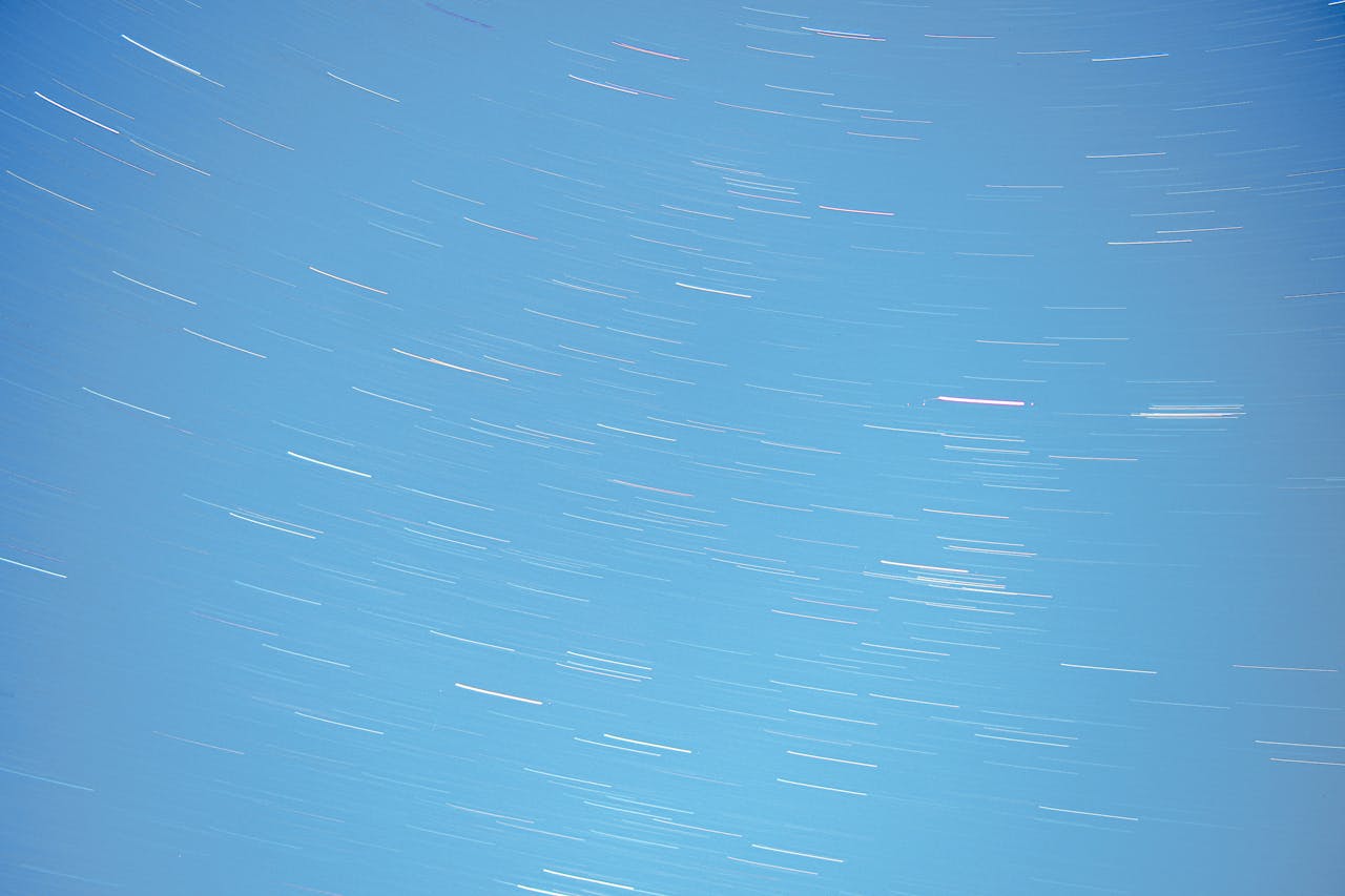 Long exposure photo of star trails creating an abstract pattern in a clear night sky.