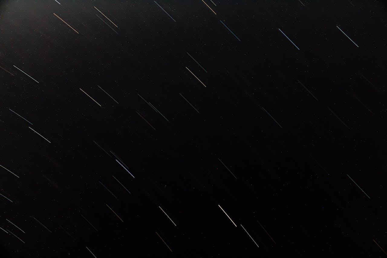 Vivid star trails streaking across a dark night sky, depicting cosmic motion.